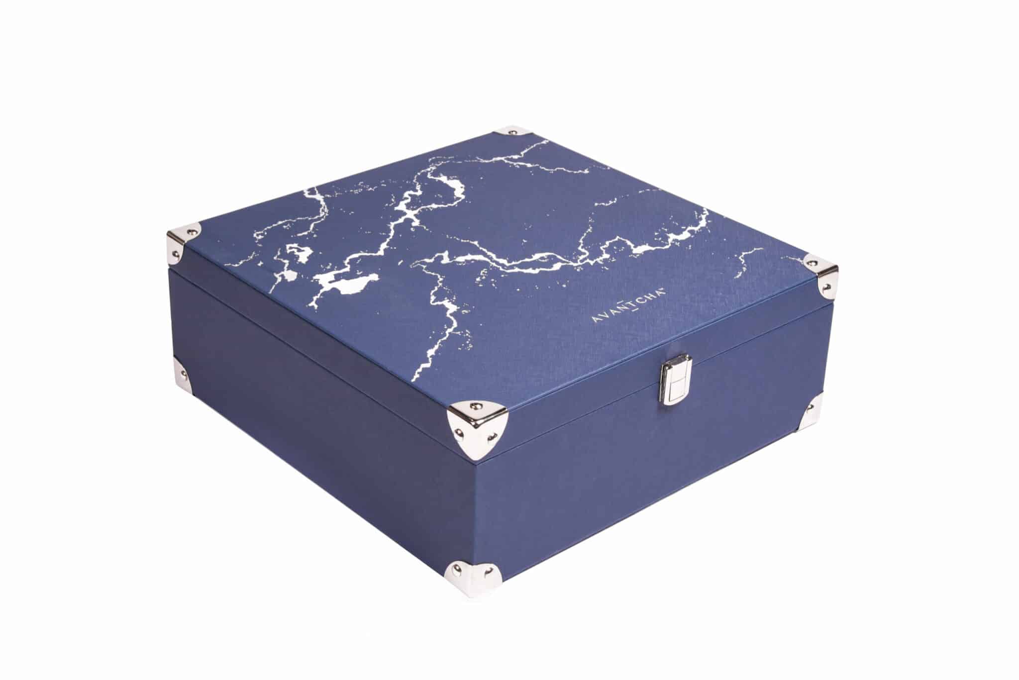 An ornate tea treasure chest filled with loose leaf tea caddy, glass teacups, glass teapot and tea timer accessories